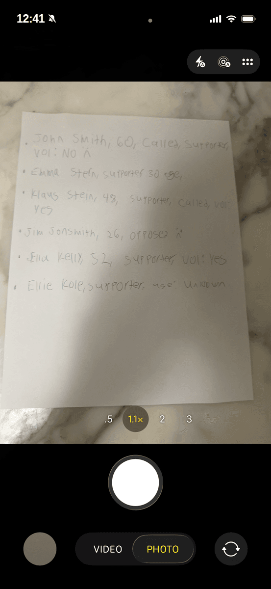 A volunteer photographs a handwritten sign-up sheet with the Threshold app camera